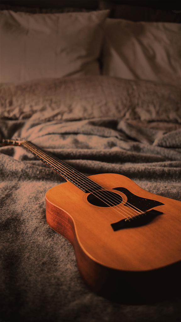 Orange guitar on bed